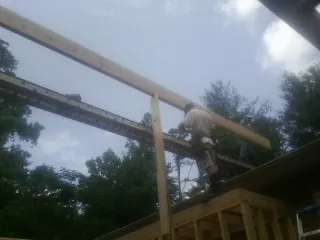 Carpenter setting a ridge beam over a new addition frame — Ice Dam Removal by Roofing Brothers in Box Springs