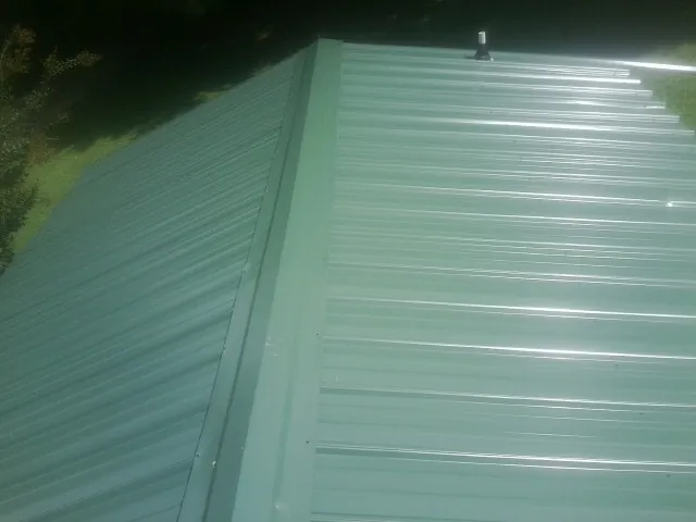 New green metal panels meeting at the ridge of a roof — Flat Roof Repair work by our crew in Box Springs