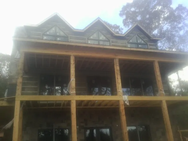 Dormers and porch framing on a large log home under construction — Roof Coating work by our crew in Box Springs