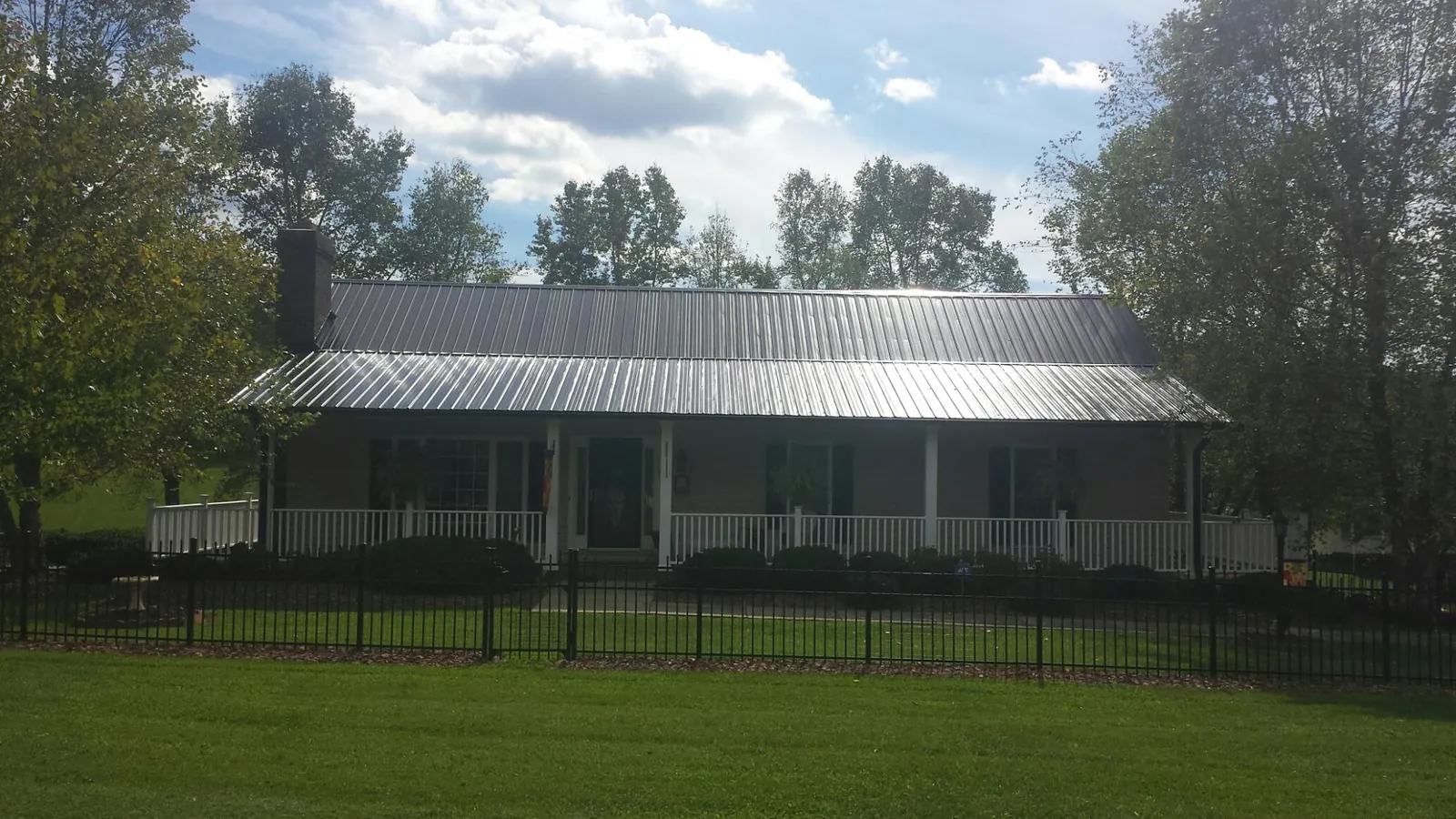Gray metal roof on a brick ranch with a full width front porch — Gutter Guard Installation work by our crew in Box Springs