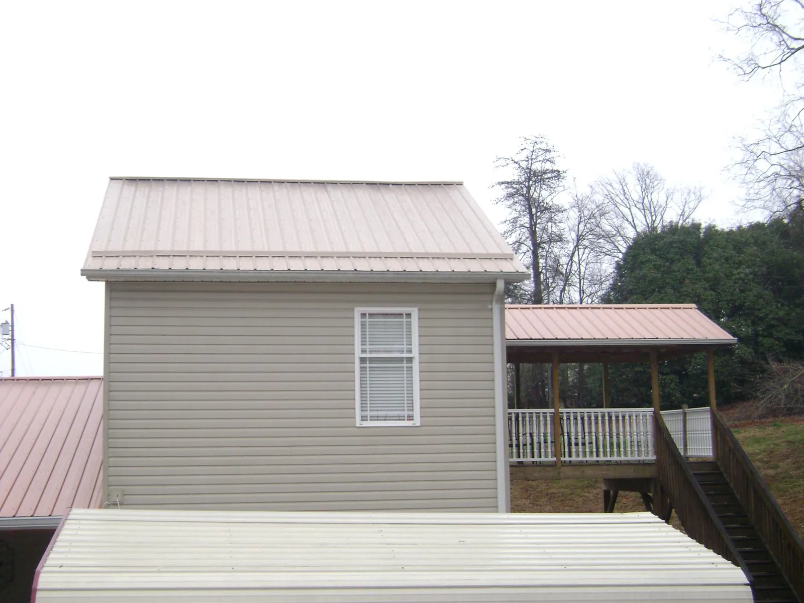 Tan metal roofs on a two story addition and attached porch, from a Roof Replacement job in Box Springs