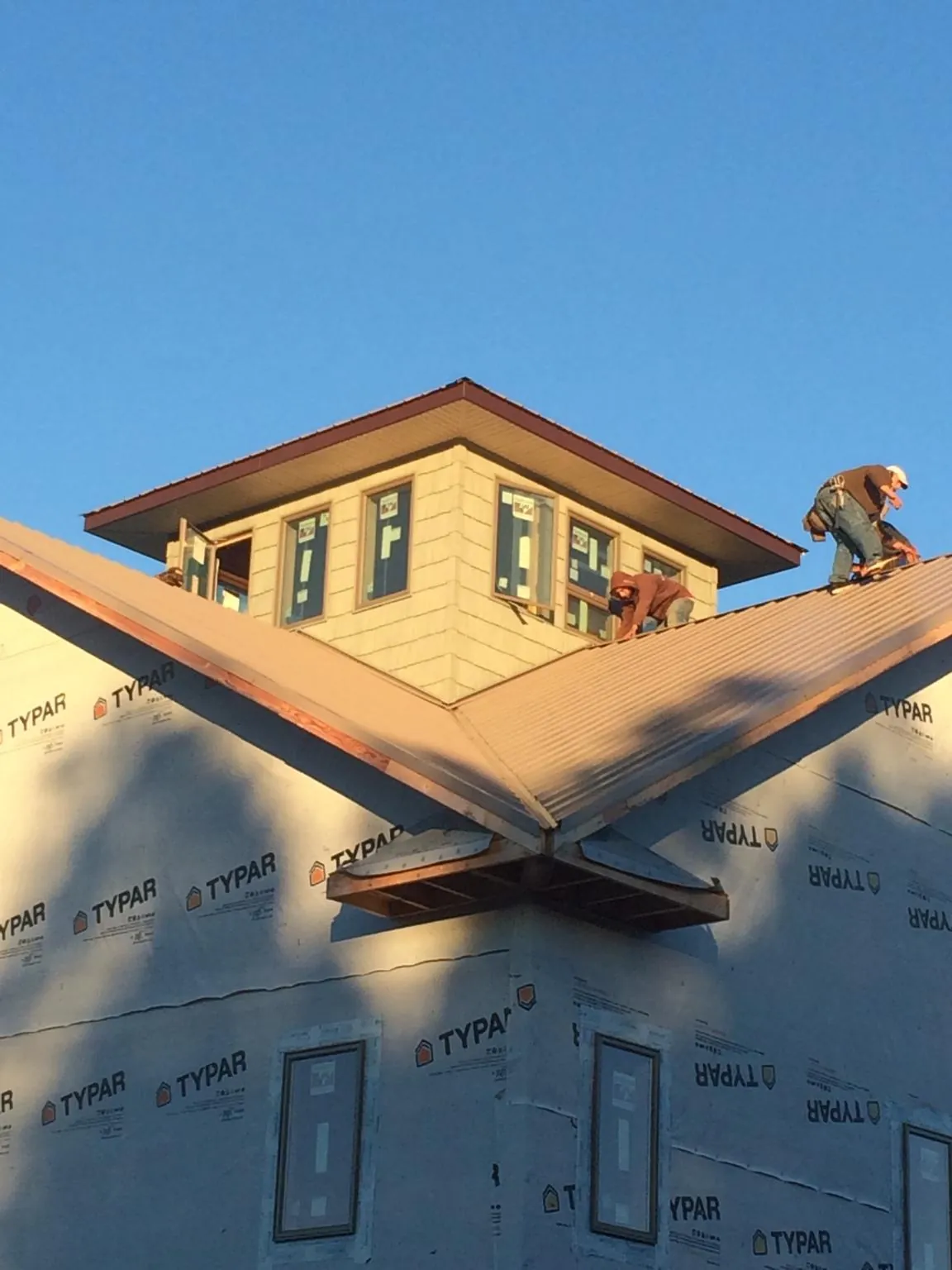 Roofers working around a rooftop cupola on a new metal roof at sunset — Roof Waterproofing in Box Springs by Roofing Brothers